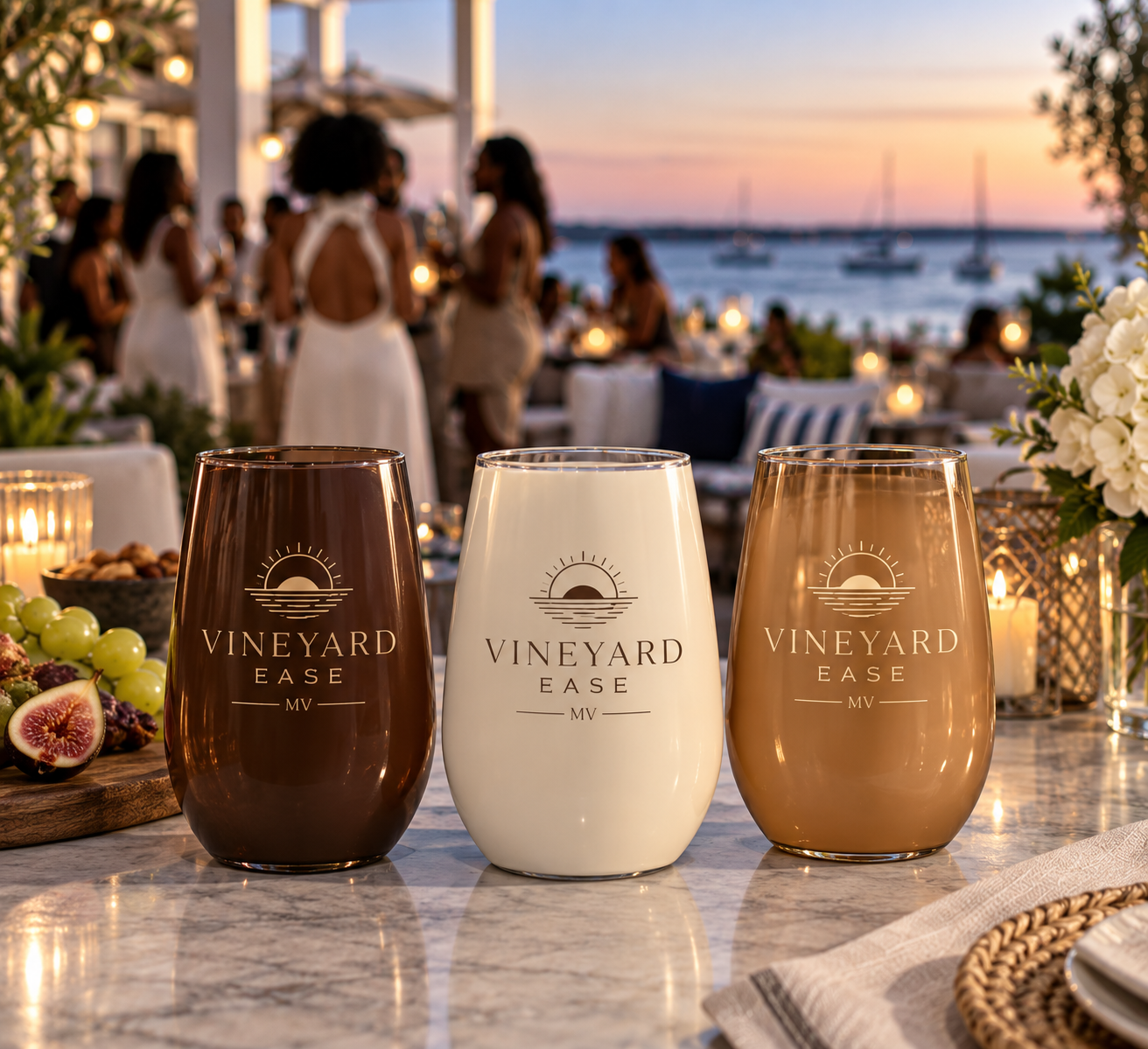 Elegant Vineyard Ease™ celebration at sunset with branded glasses and guests mingling by the water